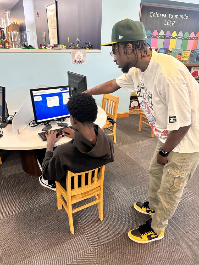 Jordan supporting a student working at a classroom computer